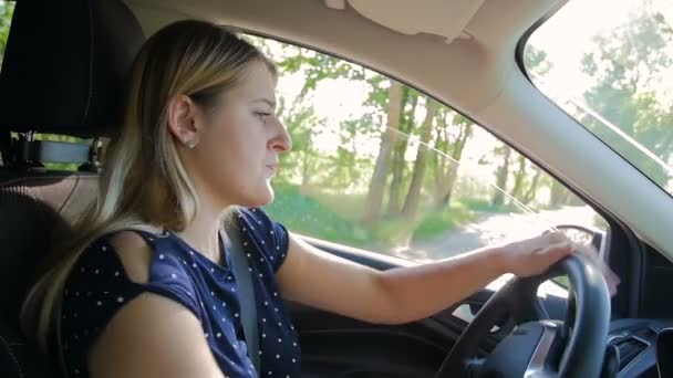 Повільне відео руху молодої жінки обертається під час водіння автомобіля та паркування — стокове відео