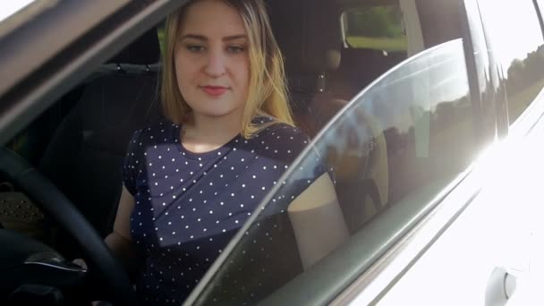 Vídeo en cámara lenta de hermosa mujer conduciendo coche abre la ventana y mirando hacia fuera en el día soleado brillante — Vídeo de stock