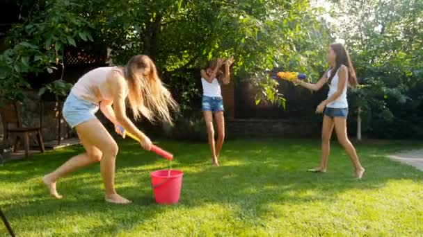 暑い夏の日に庭で水銃と水ホースで遊ぶ子供たちと陽気な若い家族のスローモーションビデオ — ストック動画