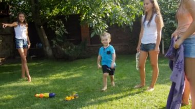 Su tabancaları ile bahçede oynayan ve birbirlerine su sıçrayan mutlu neşeli gençlerin 4k görüntüleri