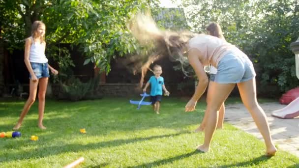 Vidéo 4k de joyeux rires d'enfants avec des parents éclaboussant l'eau les uns sur les autres à partir de pistolets à eau et tuyau d'arrosage dans la cour arrière — Video