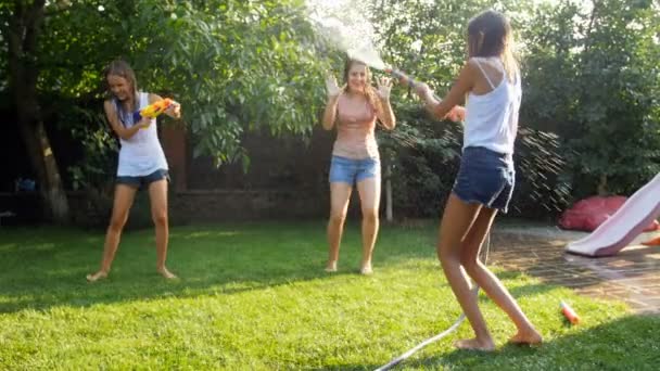 Video al rallentatore di famiglia che ha battaglia d'acqua con tubo da giardino e pistole ad acqua a casa cortile — Video Stock