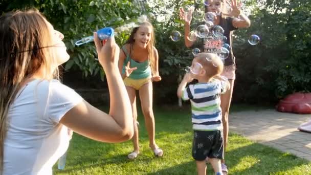 Parkta sabun kabarcıkları ile eğlenen çocuklu genç annenin 4k yavaş çekim görüntüleri — Stok video