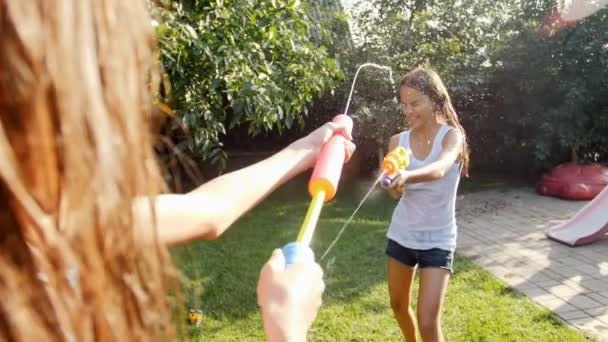 暑い夏の日に水銃と庭のホースで遊ぶ子供たちのスローモーション映像。すべての服が濡れる — ストック動画