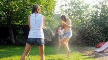 Mutlu aile arka bahçesinde birbirlerine su sıçrayan yavaş hareket video