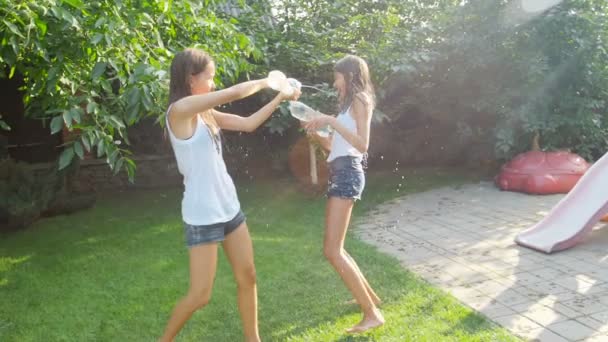 Slow motion video van gelukkige kinderen en volwassenen spatten water van waterpistolen en tuinslang over elkaar op warme zonnige dag — Stockvideo