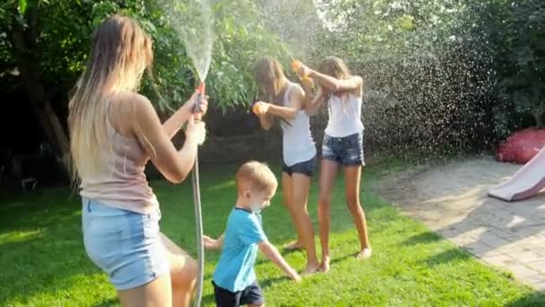 Evin arka bahçesinde bahçe hortumu ve su tabancaları ile su savaşı olan ailenin Yavaş hareket video — Stok video