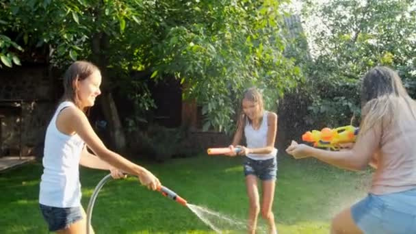 Filmati al rallentatore di bambini che giocano con pistole ad acqua e tubi da giardino nelle calde giornate estive. Tutti i vestiti si bagnano — Video Stock