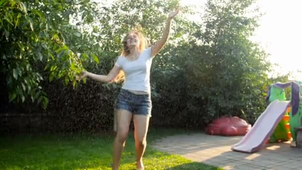 Slow motion video av glad ung kvinna dansar och njuter sommarregn vid solnedgången — Stockvideo