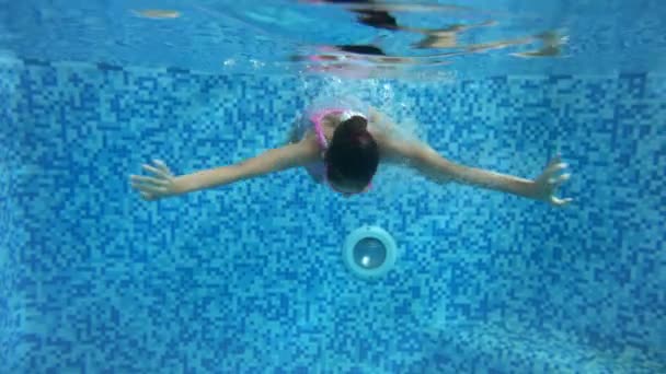 4k кадри підлітка усміхненої дівчини в окулярах для дайвінгу та плавання під водою в критому басейні в тренажерному залі — стокове відео