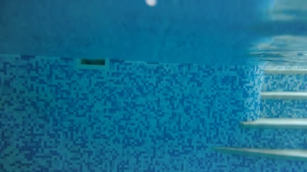4k video de una adolescente buceando bajo el agua en la piscina. Vista desde la superficie del agua — Vídeo de stock