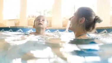 Spor salonunda annesi ile yüzme gülümseyen yürümeye başlayan çocuk 4k video. Mutlu aile suda oynarken ve yüzmenin tadını çıkarır