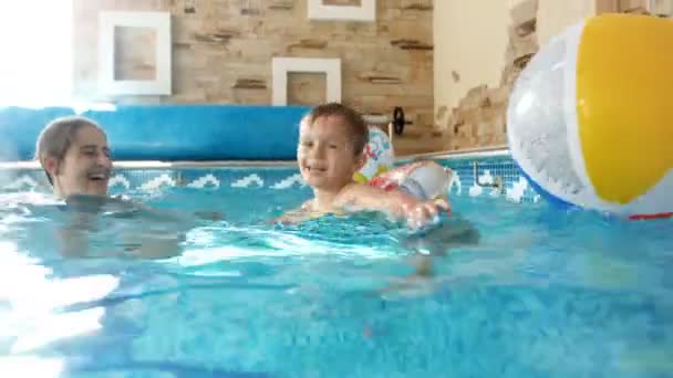 Imágenes de 4k de la familia alegre feliz jugando en la piscina con la bola inflable colorida de la playa — Vídeo de stock