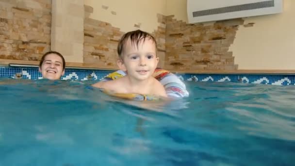 4k metraje de sonriente bola de niño nadando en la piscina con anillo inflable. Aprendizaje infantil nadar — Vídeo de stock