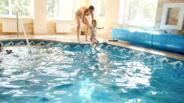 4k filmato di giovane madre mettere il suo bambino figlio in piscina in palestra — Video Stock