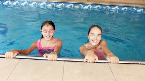 Vidéo 4k de deux adolescentes en maillots de bain colorés nageant dans la piscine intérieure — Video