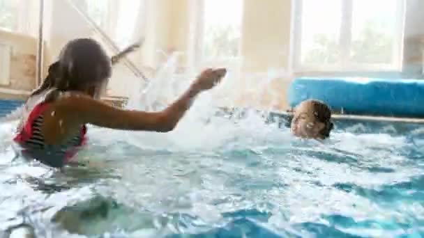 4k filmato di due ragazze che giocano in piscina. Bambini spruzzando e avendo lotta in acqua — Video Stock