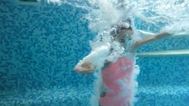 Yüzme havuzunda su altında dalış genç kız 4k video. Su yüzeyinin altından görünüm