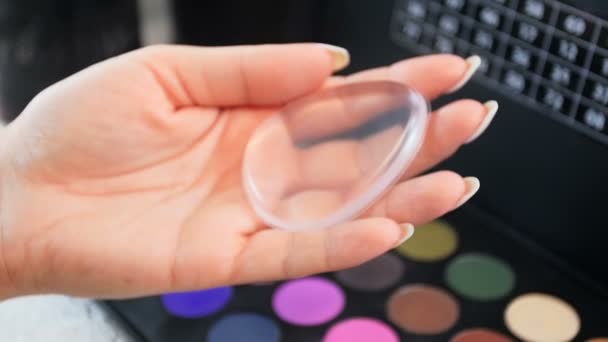 特写慢动作视频女性化妆师持有透明硅胶施用器，用于在脸上涂抹化妆 — 图库视频影像