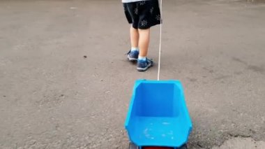 Küçük yürümeye başlayan çocuk yürüyen ve halat ile oyuncak kamyon çekerek 4k video