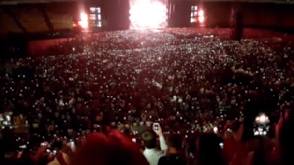 밤에 큰 경기장에서 큰 록 콘서트의 4K 흐린 영상. 사람들은 스포츠 경기장에서 춤을 추고 노래를 부른다. 완벽한 배경 또는 배경 — 비디오