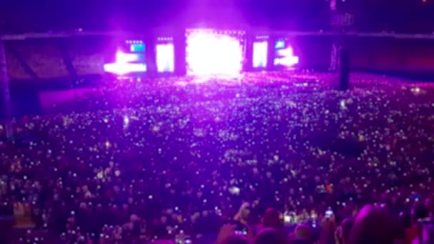 Des images floues de 4k d'un grand concert de rock sur un grand stade la nuit. Les gens dansent et chantent sur la scène sportive. Contexte parfait ou toile de fond — Video