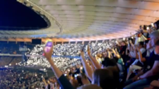 Imágenes de 4k de fans alegres cantando y agitando con teléfonos inteligentes brillantes y encendedores en concierto de rock en el estadio . — Vídeos de Stock