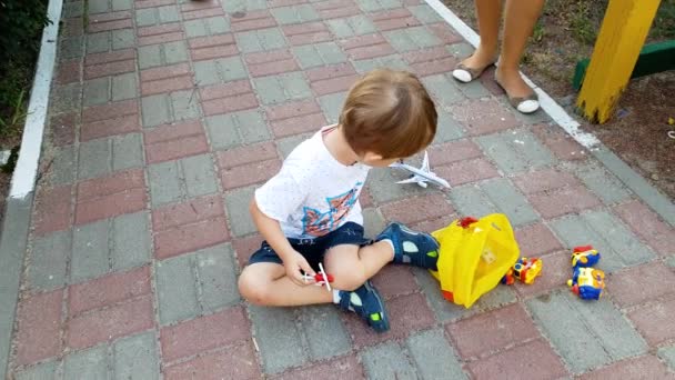 Vidéo 4k de 3 ans tout-petit garçon jouant sur l'aire de jeux avec des voitures jouets et avion — Video