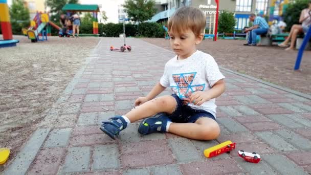 おもちゃの車や飛行機で遊び場で遊ぶ3歳の幼児の男の子の4kビデオ — ストック動画