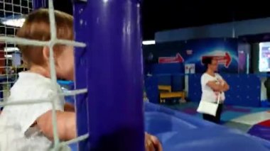 Sevimli 3 yaşındaki küçük çocuk oyun alanında slayt sürme 4k görüntüleri. Alışveriş merkezindeki lunaparkta eğlenen çocuklar