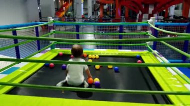 Alışveriş merkezinde oyun alanında trambolin üzerinde atlama neşeli gülümseyen yürümeye başlayan çocuk 4k video