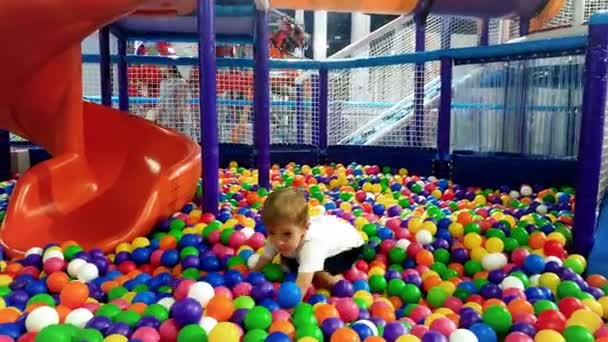 4k metraje de 3 años de edad niño jugando con bolas de colores en el patio de la piscina — Vídeos de Stock