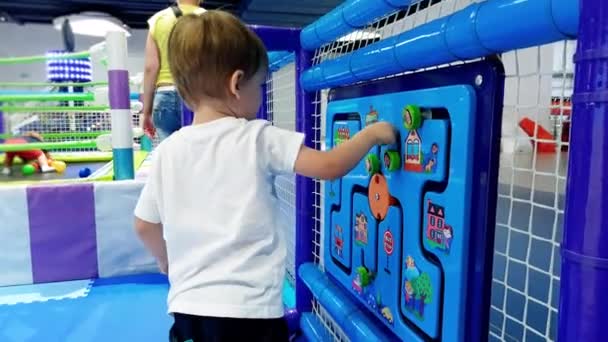 Imágenes de 4k del niño jugando con un juguete lógico de madera en el patio de recreo. Niño resolviendo laberinto. Juegos educativos para la generación creciente — Vídeo de stock