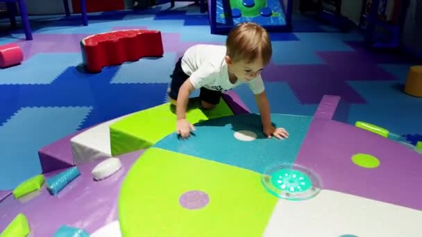 4k video de niño pequeño escalando y jugando en un patio de recreo suave en el parque de atracciones. Niños activos divirtiéndose — Vídeos de Stock