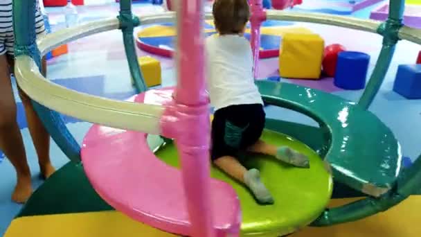 ショッピングモールの遊園地でカラフルなカルーセルに乗る幼児少年の4kビデオ — ストック動画