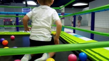 Oyun alanında trambolin üzerinde oynarken pand atlama neşeli todler çocuk 4k görüntüleri. Alışveriş merkezindeki lunaparkta eğlenen çocuklar