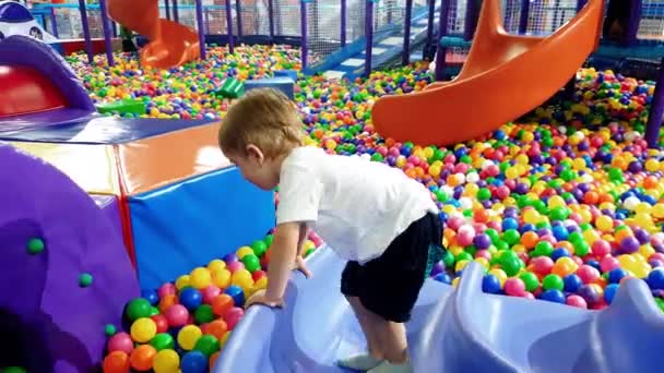 4k vídeo de criança menino escalando no playground colorido coberto com tapetes macios para a segurança da criança — Vídeo de Stock