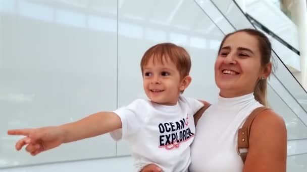 Vidéo 4k de la jeune mère souriante tenant son fils tout-petit et marchant dans le centre commercial — Video