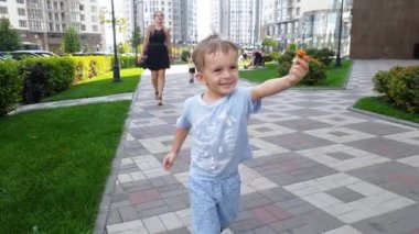 Parkta küçük oyuncak tutarak çalışan neşeli gülümseyen yürümeye başlayan çocuk 4k video