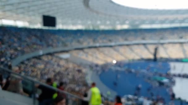 4k out of focus panning video of crowd of fans in fan zone and people seating on seats on stadium srena waiting for the begging of rock concert at evening — Stock Video