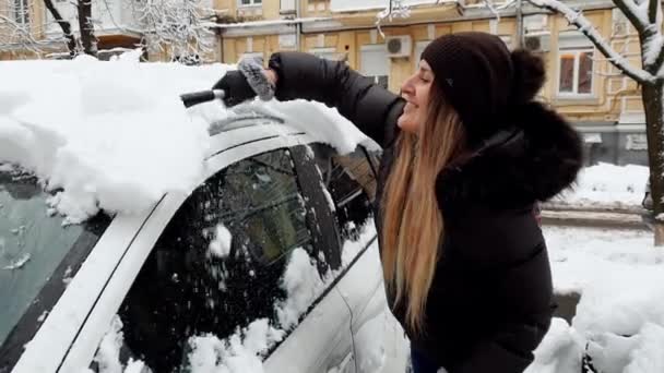 4k video de hermosa conductora femenina limpiando su coche de la nieve después de ventisca en la mañana — Vídeo de stock