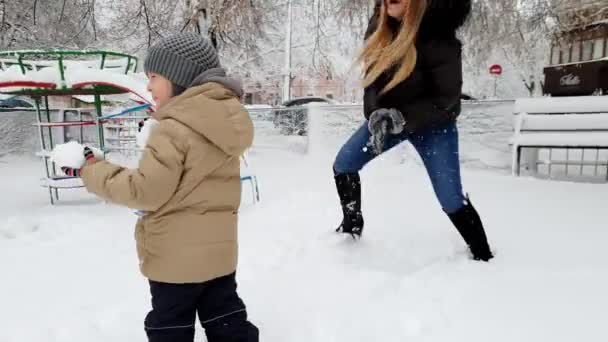 4K bilder av ung mor med sitt småbarn son med snöboll Fight på lekplats på Park — Stockvideo