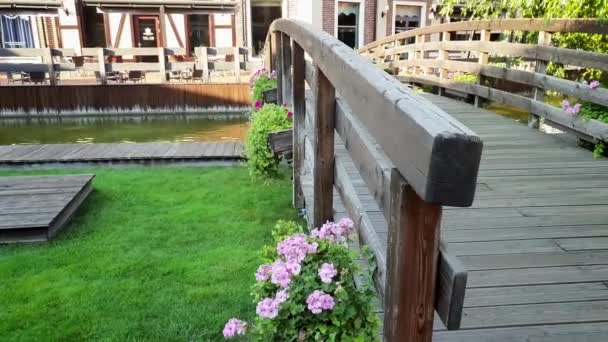 4k video of beautiful old wooden bridge with flower pots over water canal in small european town at summer — Stock Video