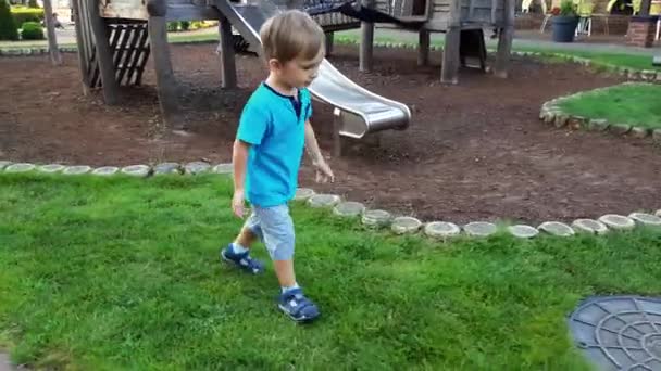 4k видео улыбающегося мальчика, бегущего в красивом летнем парке — стоковое видео
