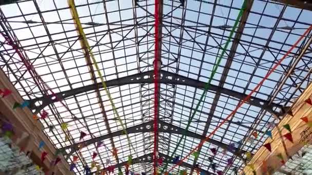 Materiał 4K z pięknym szklanym dachem w centrum handlowym ozdobiony kolorowymi wstążkami na święta — Wideo stockowe
