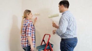 Yeni dairelerinde boya rulo ile duvar boyama mutlu genç çift Video yenileme altında