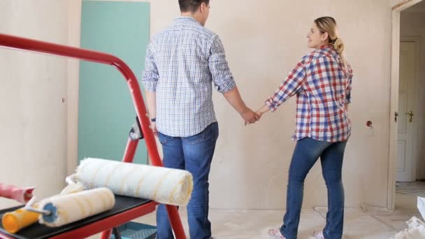 Медленная съемка веселой молодой пары, дающей друг другу пять и улыбающейся во время ремонта в своей новой квартире — стоковое видео