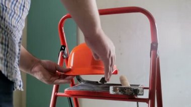 İnşaat altında evde yürüyen elinde kırmızı hardhat ve çekiç tutan genç erkek işçi closeup yavaş hareket video