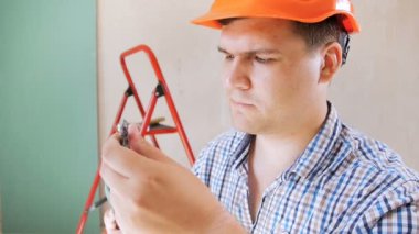 Kırmızı hardhat matkap bit ekleme ve kamera bakarak gülümseyen erkek işçi ir oluşturucu Closeup yavaş hareket video