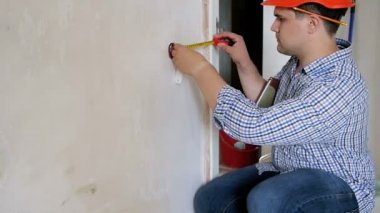 Erkek inşaat işçisi veya inşaatçının ölçüm yapıp hesaplamasını not defterine yazmasının yavaş çekim görüntüleri. İnşaat veya tadilat tasbısıaltında evde çalışan yüklenici